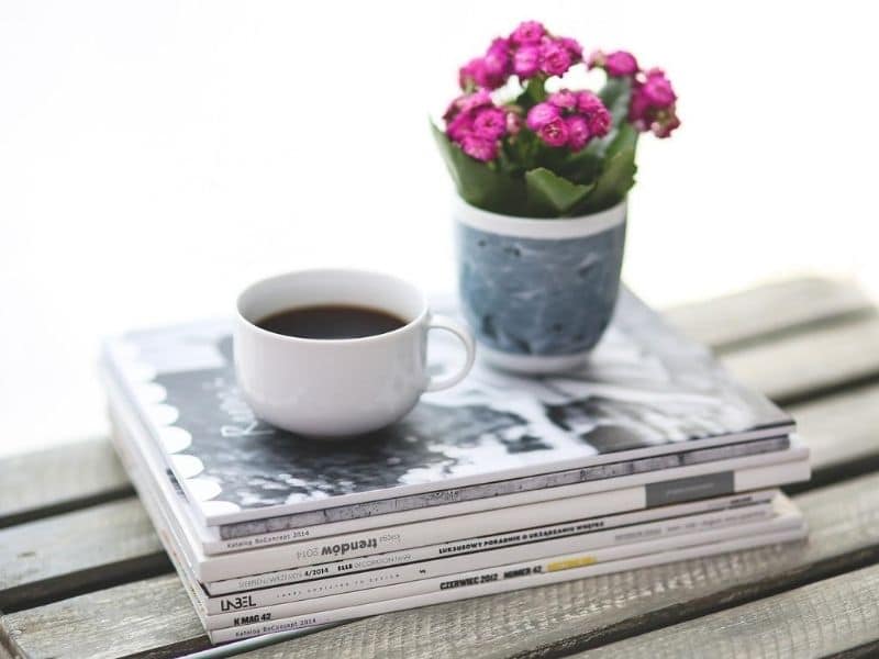 cup of coffee and flowers on magazines